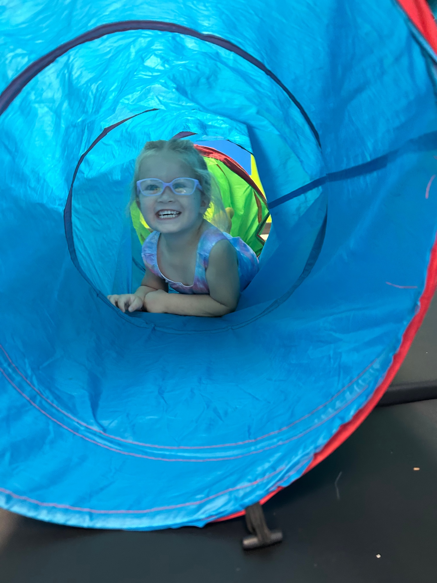 Preschool dancer peeking through play tunnel